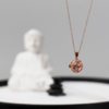 A zen garden lifestyle shot of our rose gold aromatherapy necklace with a Buddha